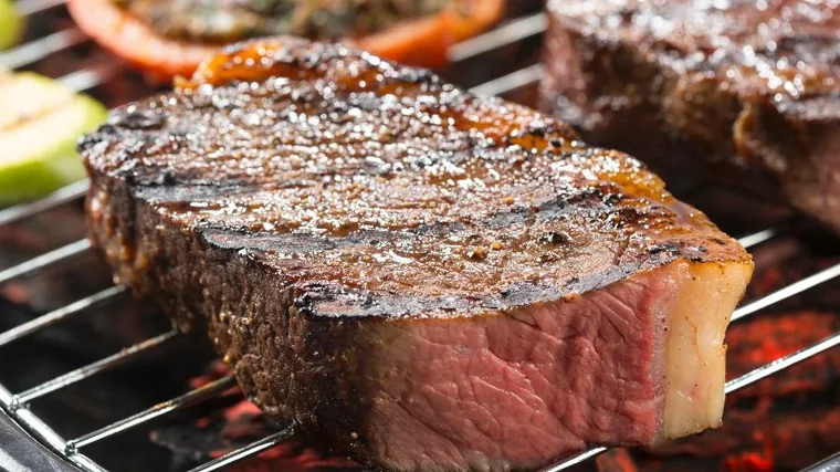 Carne grelhando na churrasqueira.